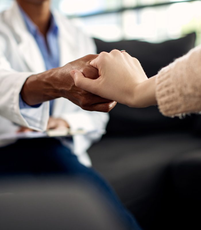 Close-up of a compassionate therapist holding hands with her patient during a session.
